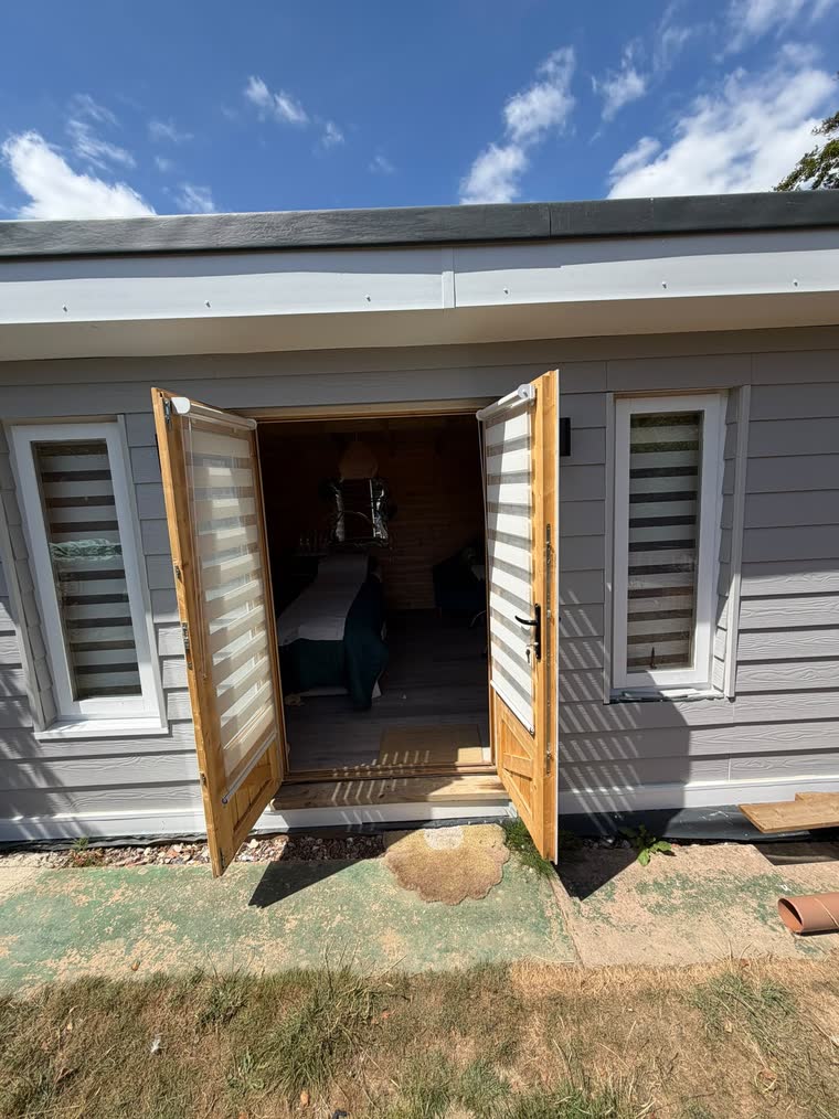 The garden treatment cabin in Polegate, its double doors open onto the lawn