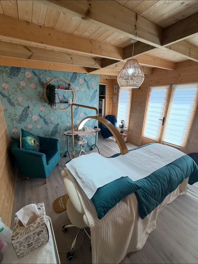 The treatment room seen wide, warm pine walls meeting a peacock-patterned feature wall